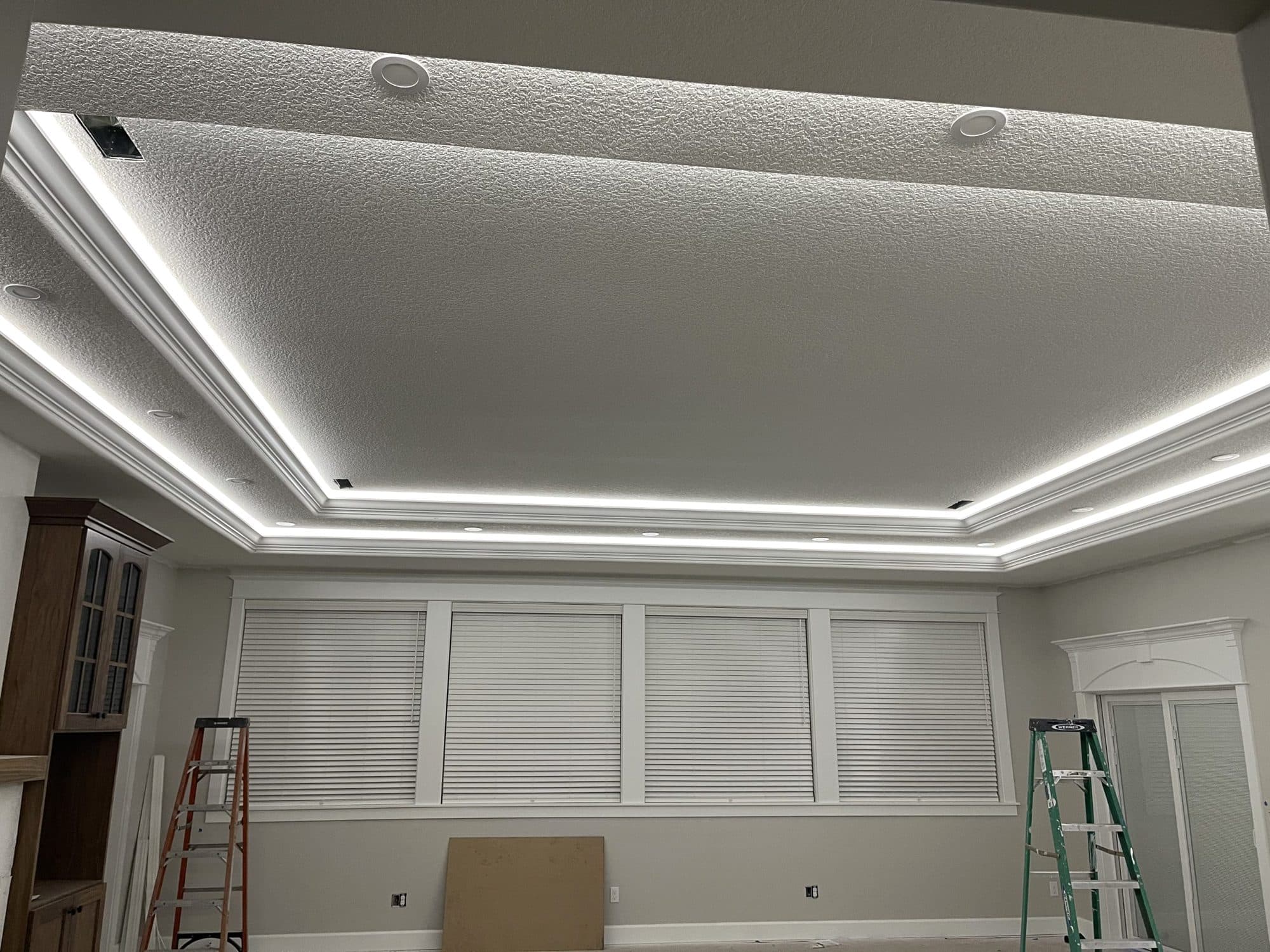 A tray ceiling lit by a glowing LED cove line, with recessed lights around the edge of the room.